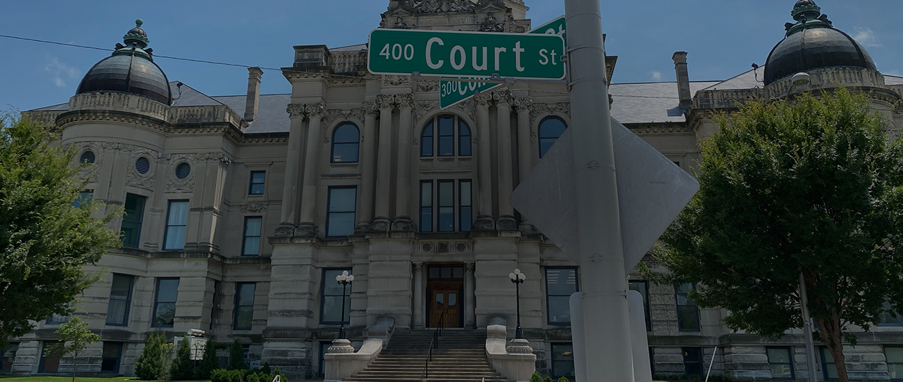 A street sign reading 400 Court St in front of a historic courthouse building with a prominent clock tower.